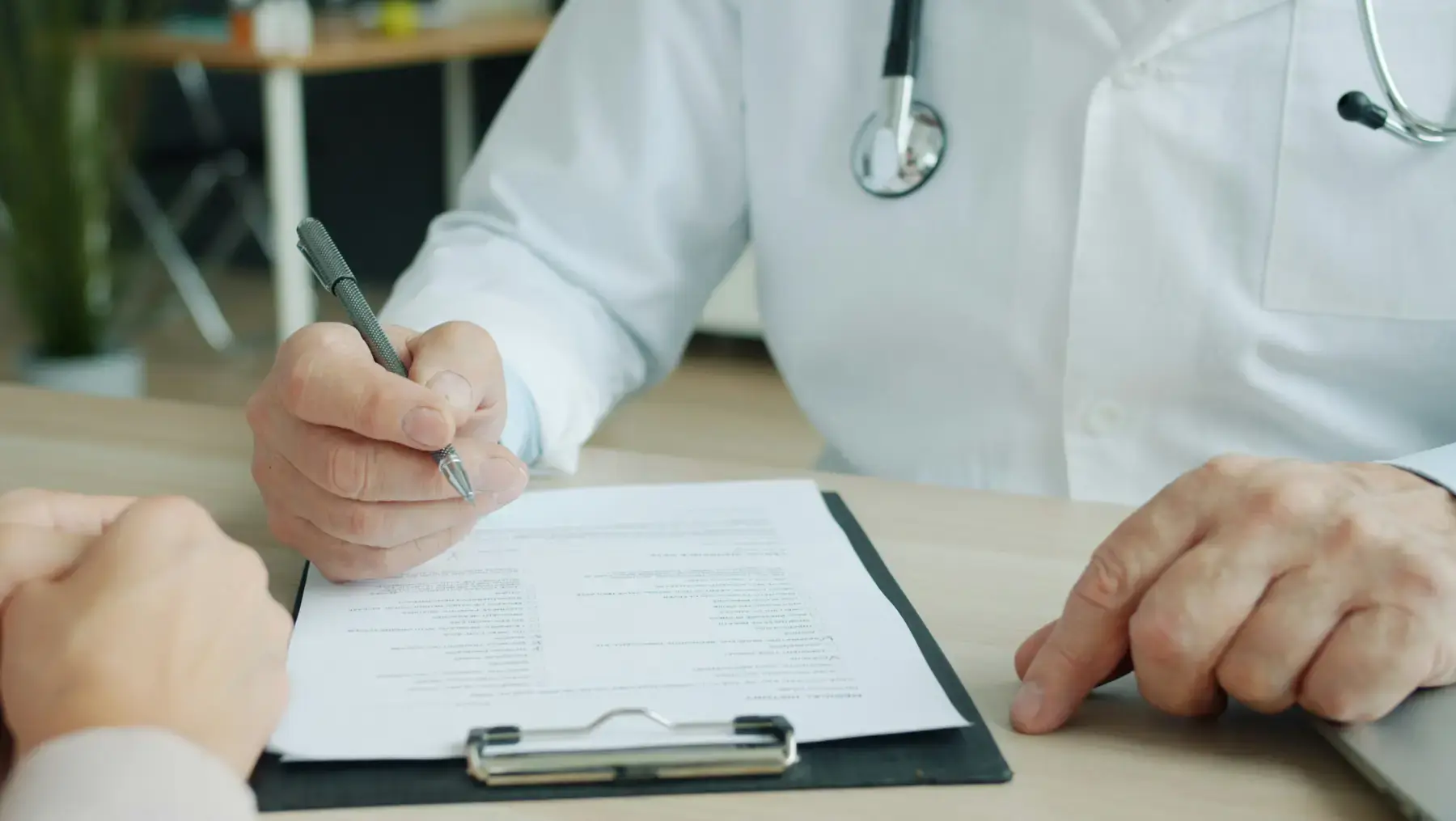 Doctor in a white coat completing paperwork at a desk